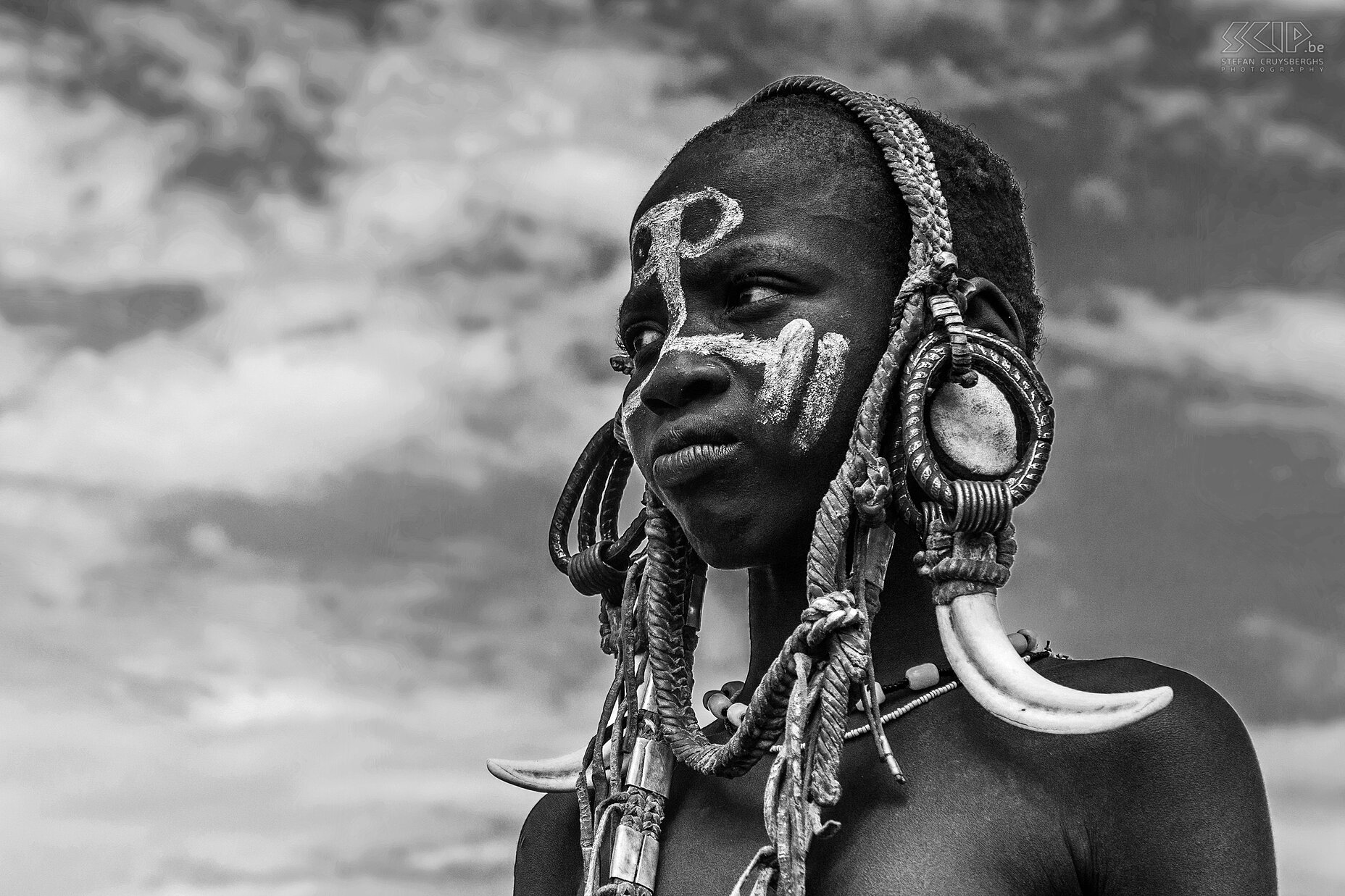 Mago - Mursi girl A young Mursi girl with a painted face and a headdress made with chains and horns of a cow . Stefan Cruysberghs